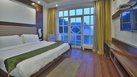 A view of a large bed next to a large bed in Premium Room at DLS Highland Resort and Spa, Mussoorie.